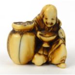 Oriental ivory Netsuke of an elderly gentleman beside a jar, 3.5cm high : For Condition Reports