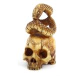 Oriental ivory Netsuke carved as a skull and a snake, 4cm high : For Condition Reports please