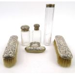 Silver items comprising two clothes brushes, ink blotter and three cut glass bottles with silver