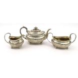 Georgian silver three piece tea service, the teapot with embossed demi fluted decoration and ivory