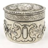 Circular silver coloured metal box with hinged lid, embossed with horse and crest and floral