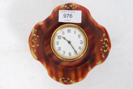 An early 20th century table clock being set within a tortoiseshell case of shaped form, the clock