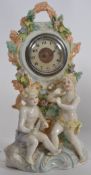 A Staffordshire bisque style mantel clock having central inset movement with cherub surrounds