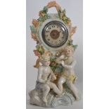 A Staffordshire bisque style mantel clock having central inset movement with cherub surrounds