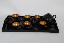 A Chinese laquered six setting tea service to include cups, saucers, spoons, creamer, sugar bowl,