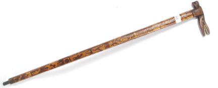 A good tribal walking stick with carved inlaid twin wood detailing having bone teeth alligator
