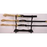 A 20th century set of graduating oriental Samurai swords - each with faux ivory handles, inset eyes.