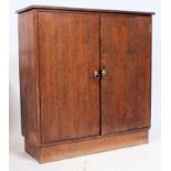 A 1950's solid oak school cupboard raised on plinth base with twin doors having single shelf within