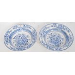 A pair of 19th century blue and white soup plates with central flower basket design having unusual