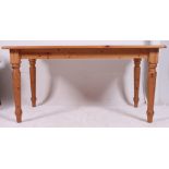 A contemporary country style pine kitchen / dining table raised on turned legs with a flared top