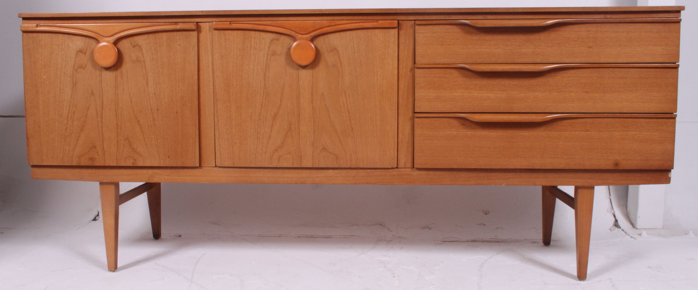 A retro 1970's Danish style teak wood low sideboard dresser raised on turned legs with a series of