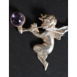 A silver hallmarked broach of a Cherub playing a pipe blowing a bubble set with an amethyst stone 8.