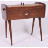 A vintage 1950's retro cantilever / metamorphic sewing box raised on tapered supports having