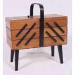 A 1950's beech and ebonised metamorphic sewing box having sectional extending body with handle to