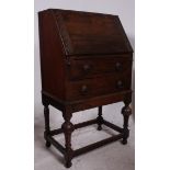 A 1930's oak ladies writing bureau being raised on gun barrel supports under a chest with fall