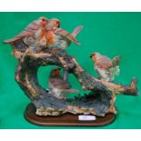 A group of 4 porcelain robins on a wood