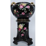 A Victorian ceramic planter and stand, in black with decorative panels depicting florals.