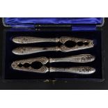 A Victorian cased set of silver plated cast iron nut crackers having chased decoration with shaped