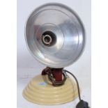 A retro vintage heat lamp having metal painted shade raised on an adjustable cast metal stand.