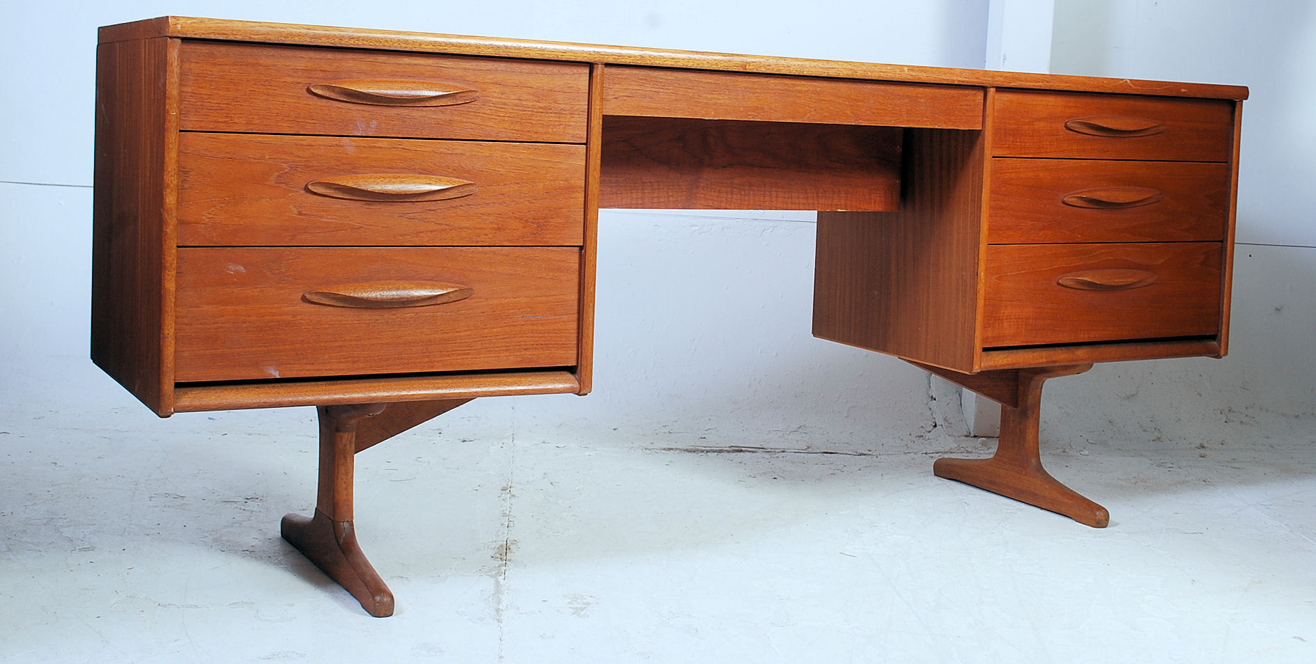 A 1950's large teak wood Danish style writing table desk - dressing chest being raised on angled