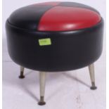 A retro two tone vinyl red and black footstool pouffe, standing on tapered retro legs.