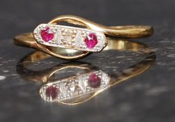 An 18ct gold ruby and diamond ring. The 3 channel set stones with central 1pnt diamond.