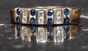 A 9ct gold hallmarked ring with 8 sapphires and 6 1pt diamonds in a band setting. Weight 2g. Size M.