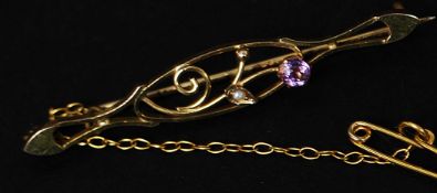 A 9ct gold bar brooch with pierced floral decoration set with a seed pearl and amethyst stone