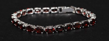 A ladies decorative silver and ruby garnet stone tennis bracelet, the stones being claw mounted. 14.