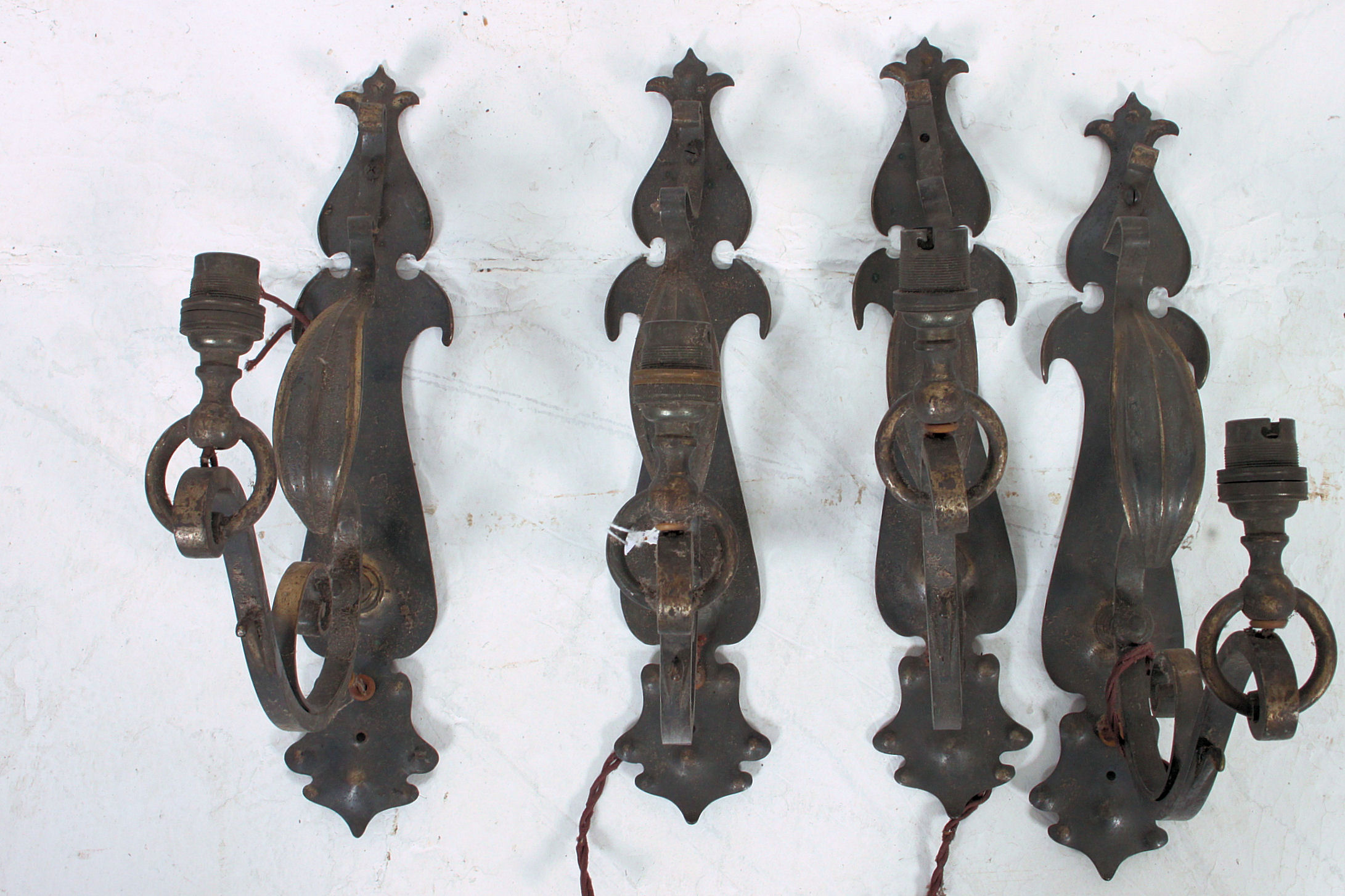 A set of 4 gilded metal wall lights having decorative sconces of scrolled form.
