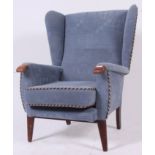 A good shaped 1950's Parker Knoll style wingback armchair raised on turned legs with blue