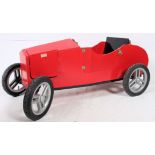 A hand built go-kart of wooden construction having red painted finish set on good pram wheels