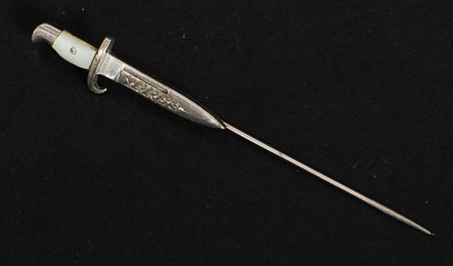 A white metal and silver stick pin - hat pin in the form of a bayonet inscribed Ypres.