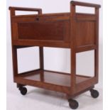 A mid century golden oak hostess trolley raised on castors with fall front sides and shaped handles