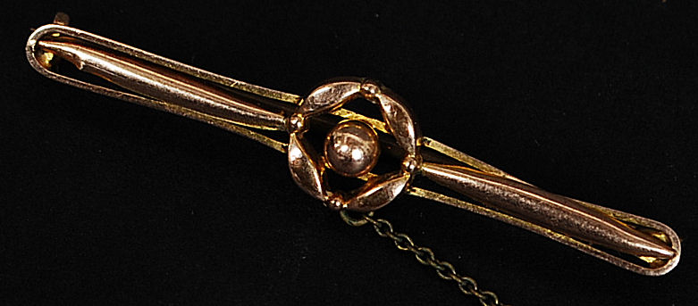 A 9ct gold bar brooch with central circular motif complete with safety chain. Weight 1.9g.