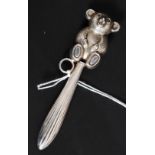 A Victorian style silver metal babies rattle, having a teddy bear abode a banded stem.