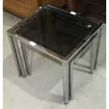 A nest of three tables with chromium-plated frames and smoke glass tops.