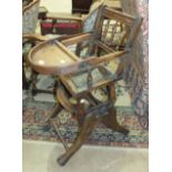 An Edwardian child's stained wood high chair on iron wheels.