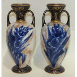 A pair of Doulton Burslem two-handled vases decorated with blue and white flowers, 23cm high, (2).
