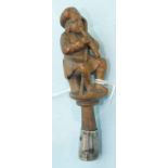 A Continental fruit wood pipe tamper in the form of a seated man playing a pipe, with shepherd's