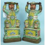 A pair of 19th century Chinese porcelain figures of crouching officials, on gilt gilt metal