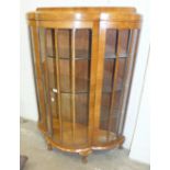 A mid-20th century walnut display cabinet, the shaped bow front fitted with a single glazed door and