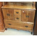 An oak low cupboard fitted with two short drawers and a base drawer, on short cabriole legs, 99cm