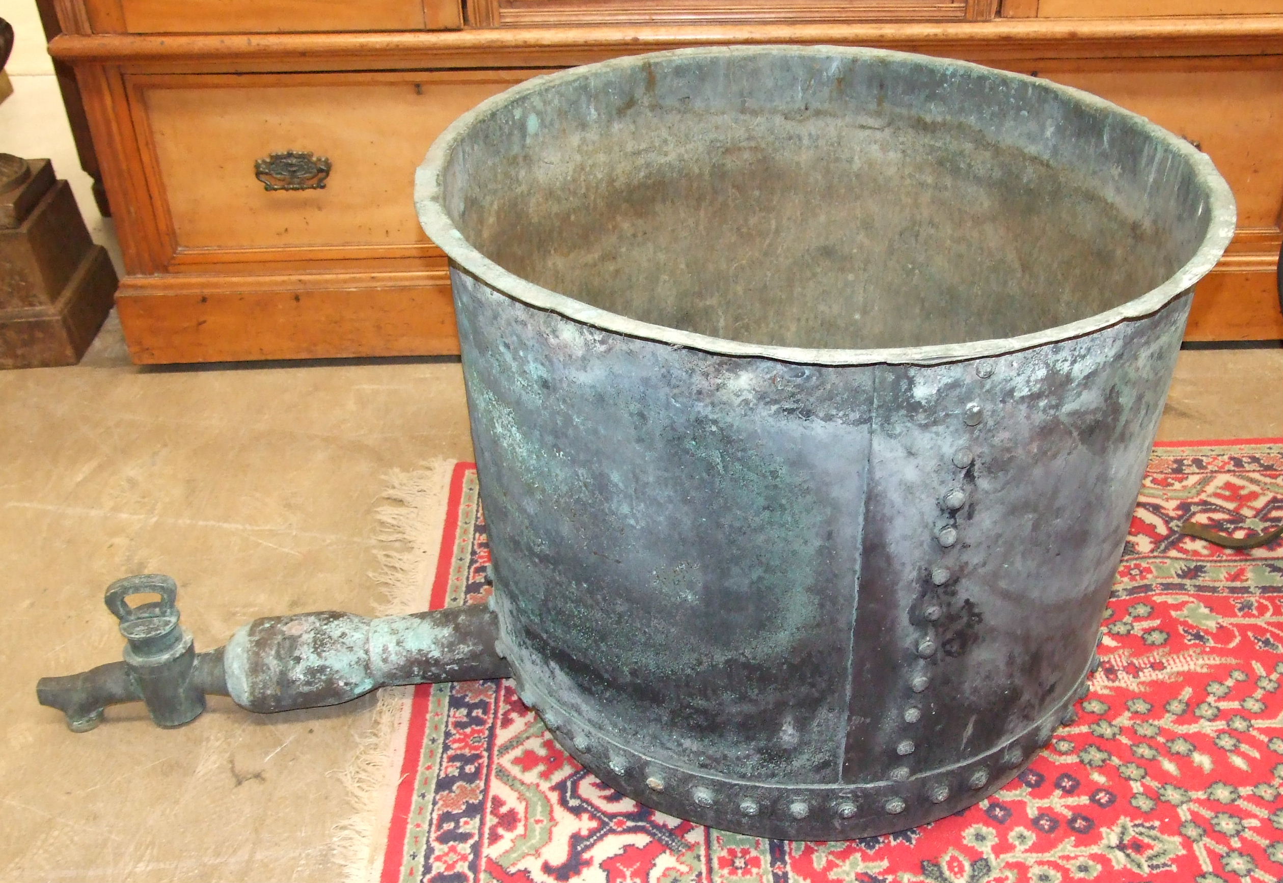 A very large circular riveted copper with tap, 57cm high.