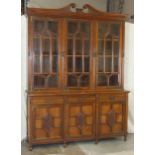 A late-19th/early-20th century good quality walnut library bookcase, the swan-necked pediment carved