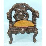 A late 19th/early 20th century ebonised wood tub chair carved with dragons and intertwined