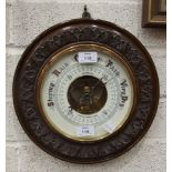 A circular aneroid barometer by Greenslade, Weston-Super-Mare mounted in circular carved oak