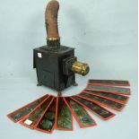 A tin magic lantern on four paw feet, with chimney, 39cm overall and ten glass slides by Ernst