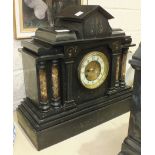 A late-Victorian black slate striking mantel clock of architectural form, having marble pillars,