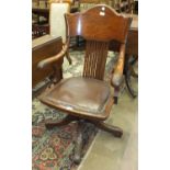 An early-20th century oak swivel office armchair, with pierced splat and padded seat, on quadruped